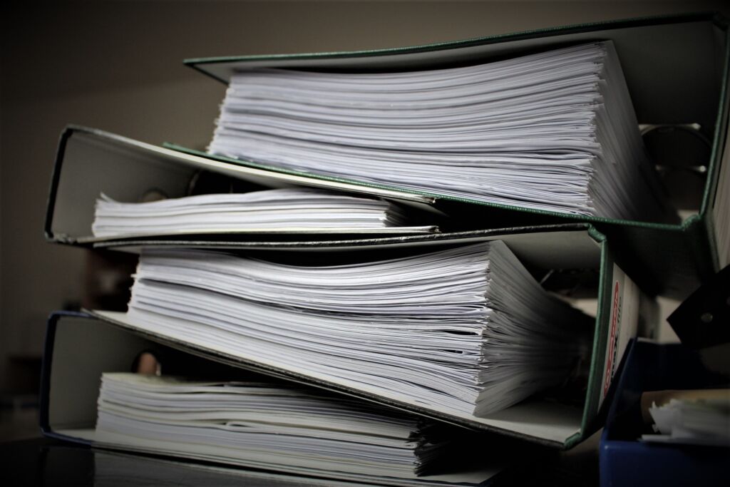 A stack of several thick binders full of papers
