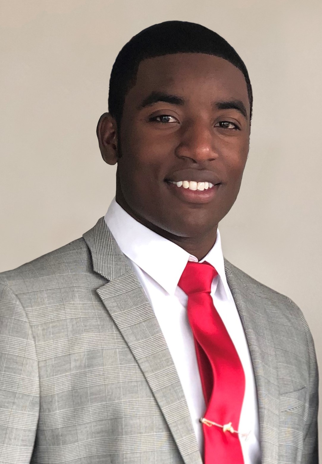 Kareem Rosser smiles. He is wearing a nice grey suit with a red tie.