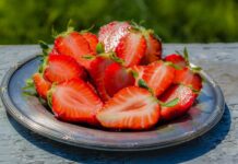 Sliced strawberries on a blue plate in the sun