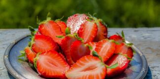 Sliced strawberries on a blue plate in the sun
