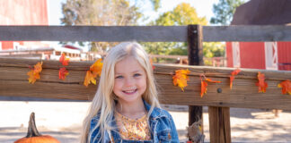 Cute little girl at the pumpkin farm in autumn
