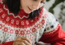 Person putting a candy cane in hot chocolate