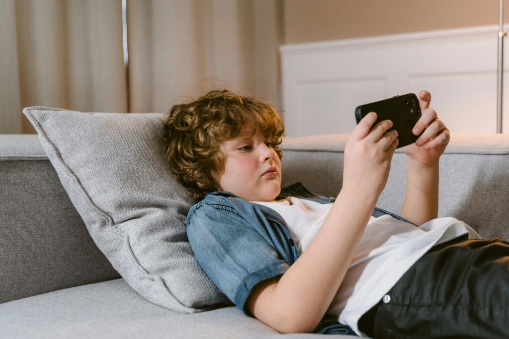 Boy laying on couch using a smartphone