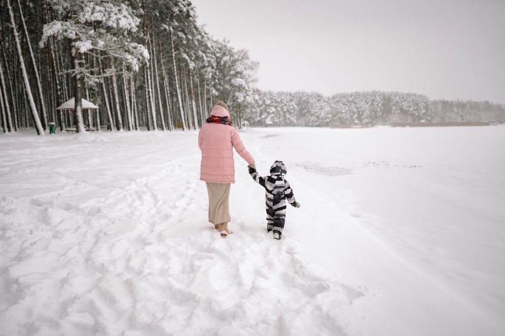 A parent leading a child through the snow