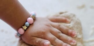 A child's hands kneading bread dough