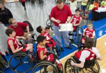A coach talking to a youth wheelchair basketball team