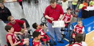 A coach talking to a youth wheelchair basketball team