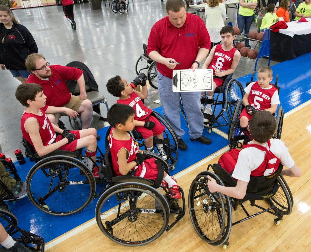 A coach talking to a youth wheelchair basketball team