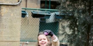 A girl holds up an Easter egg and a basket