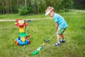 A little boy playing mini-golf