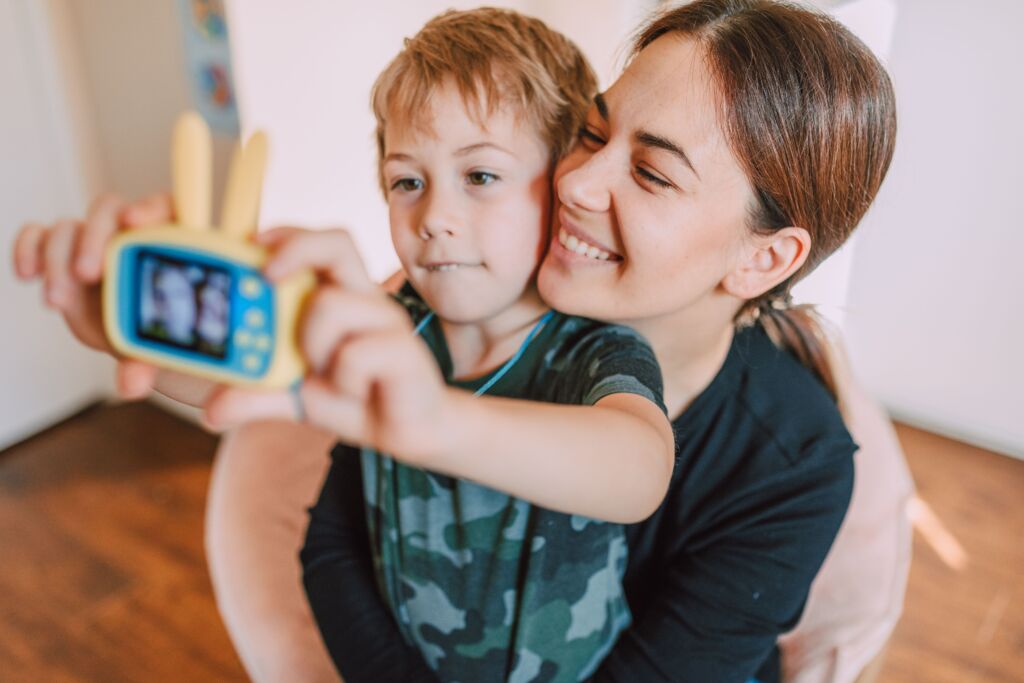 Mother and child take a selfie with a toy camera inside