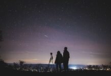 A parent and child looking at the sky with a telescope