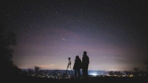 A parent and child looking at the sky with a telescope