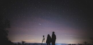 A parent and child looking at the sky with a telescope