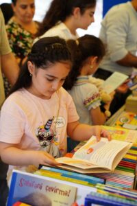 Girl reading a book at a book sale