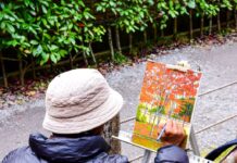 A man painting a fall scene outdoors