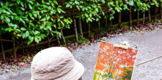 A man painting a fall scene outdoors